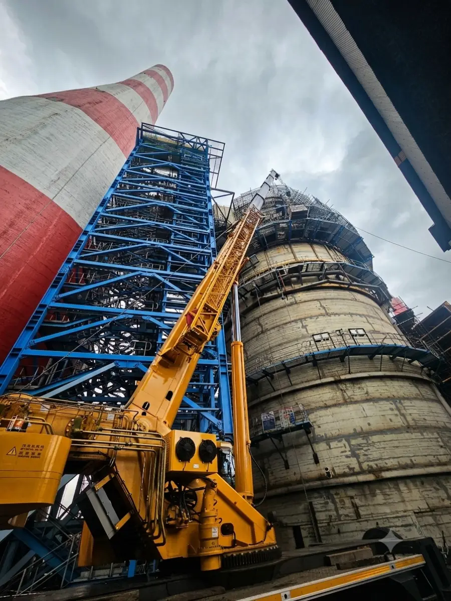 Looking up a crane boom against structural steel and the curved wall of an absorber
