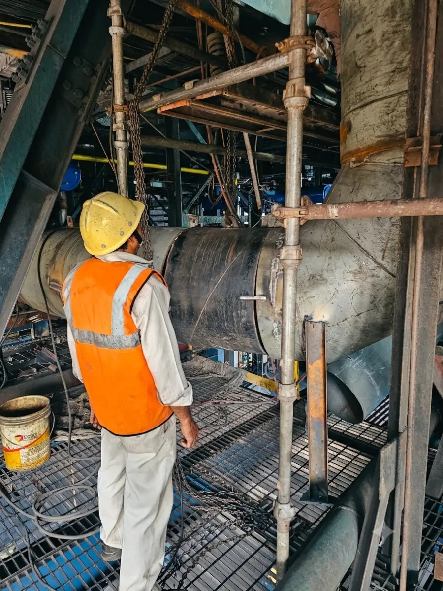 Fitter in helmet and vest working on a large pipe spool from a scaffold platform